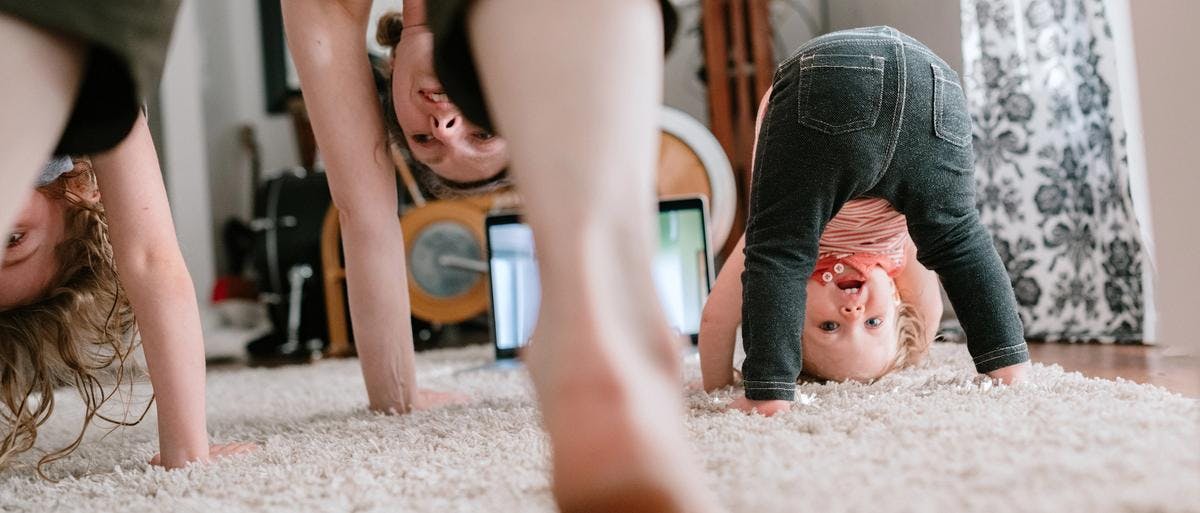 Mor og barn gjør yoga på et mykt teppe hjemme